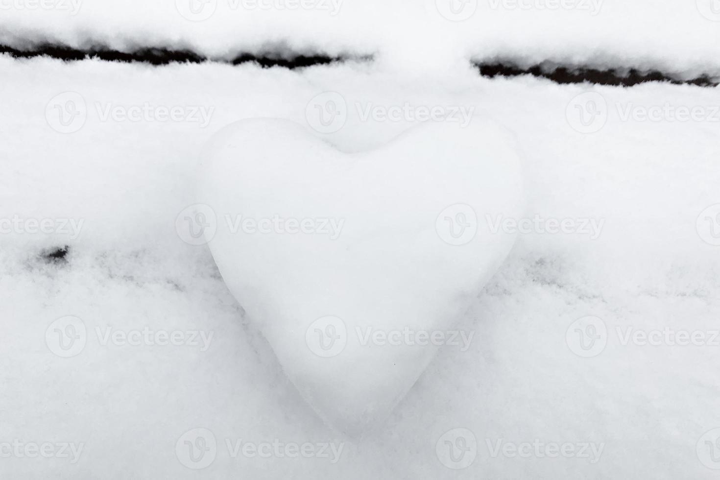 een sneeuwwit hart gemaakt van sneeuw op een bankje. het concept van valentijnsdag foto