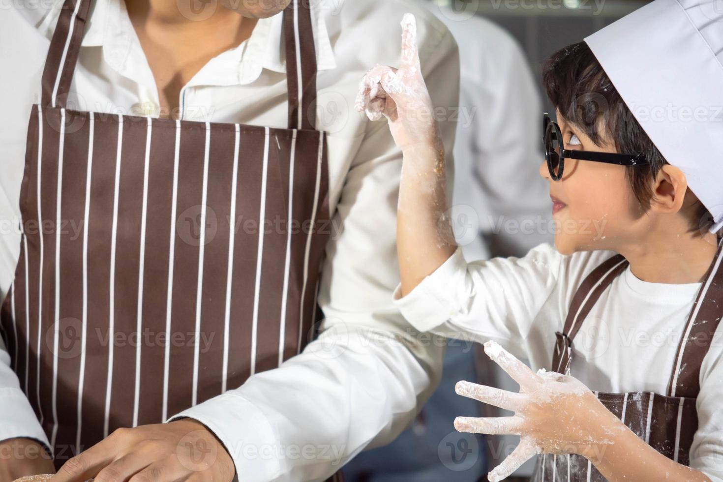 aziatische jongen bril plagen vader koken met witte bloem kneden brood deeg leert kinderen oefenen bakken ingrediënten brood, ei op servies in de keuken levensstijl gelukkig leren leven met familie foto