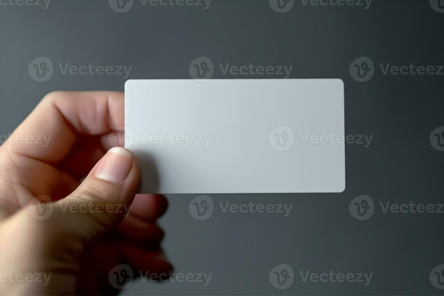 hand- Holding een blanco bedrijf kaart Aan een grijs achtergrond, dichtbij omhoog mockup foto