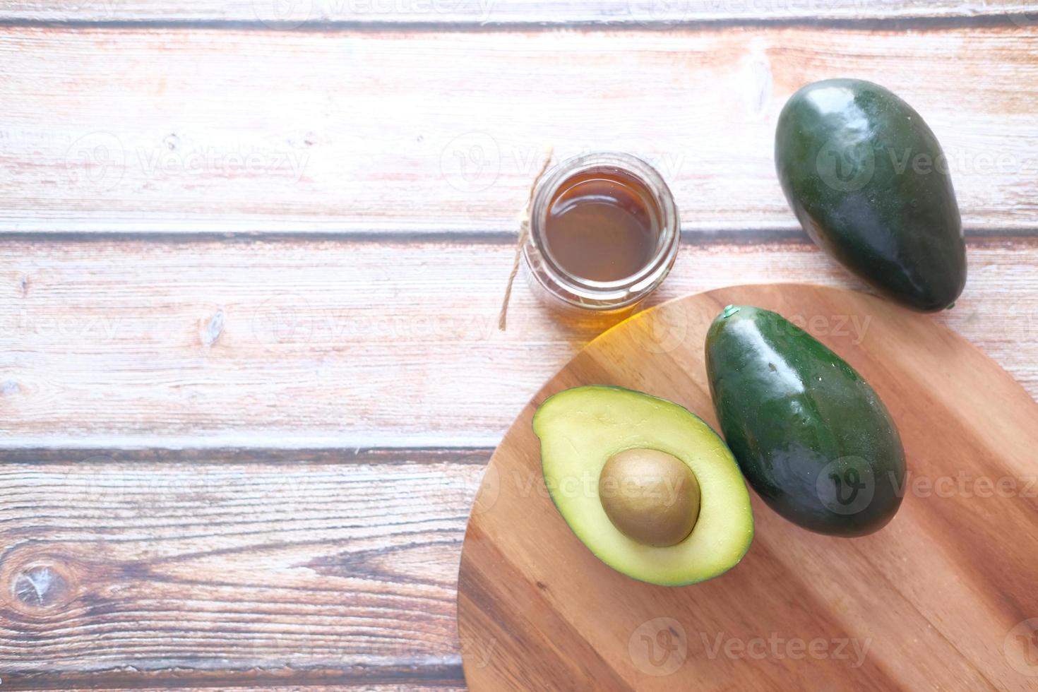 bovenaanzicht van olie en plakje avocado op houten tafel foto