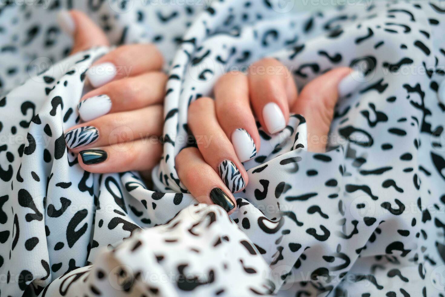 mooi vrouw handen met manicure Aan de achtergrond van luipaard kleding stof. elegant nagel ontwerp. manicure met zwart en wit zebra strepen Aan de nagels. foto