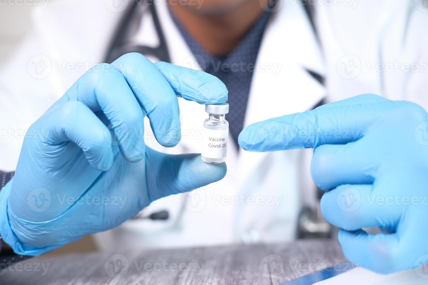 hand in latex handschoenen met glazen ampul vaccin, met kopie ruimte foto