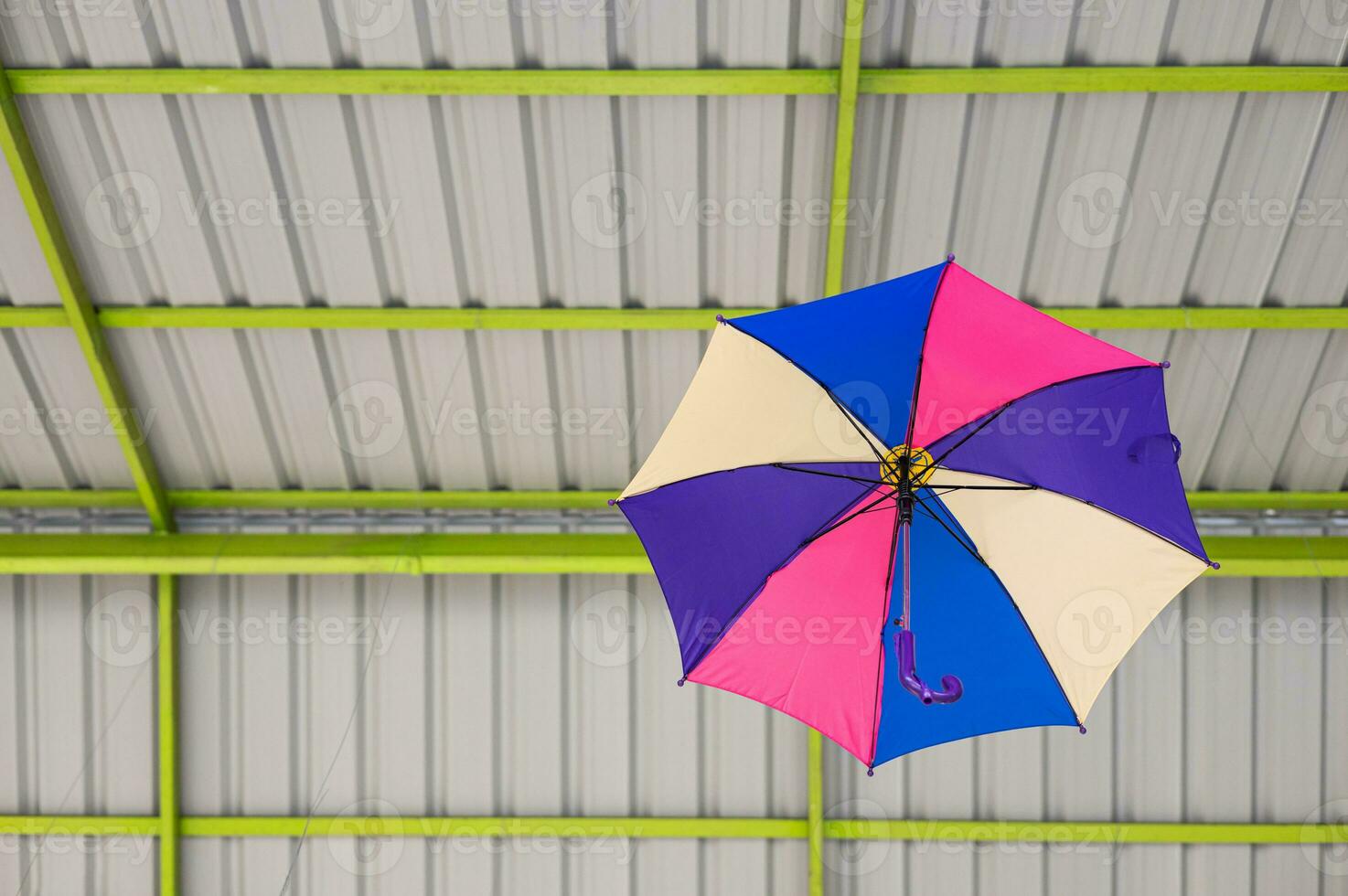 een lage hoek visie passeert door een kleurrijk versierd paraplu hangende onder een dak structuur. foto