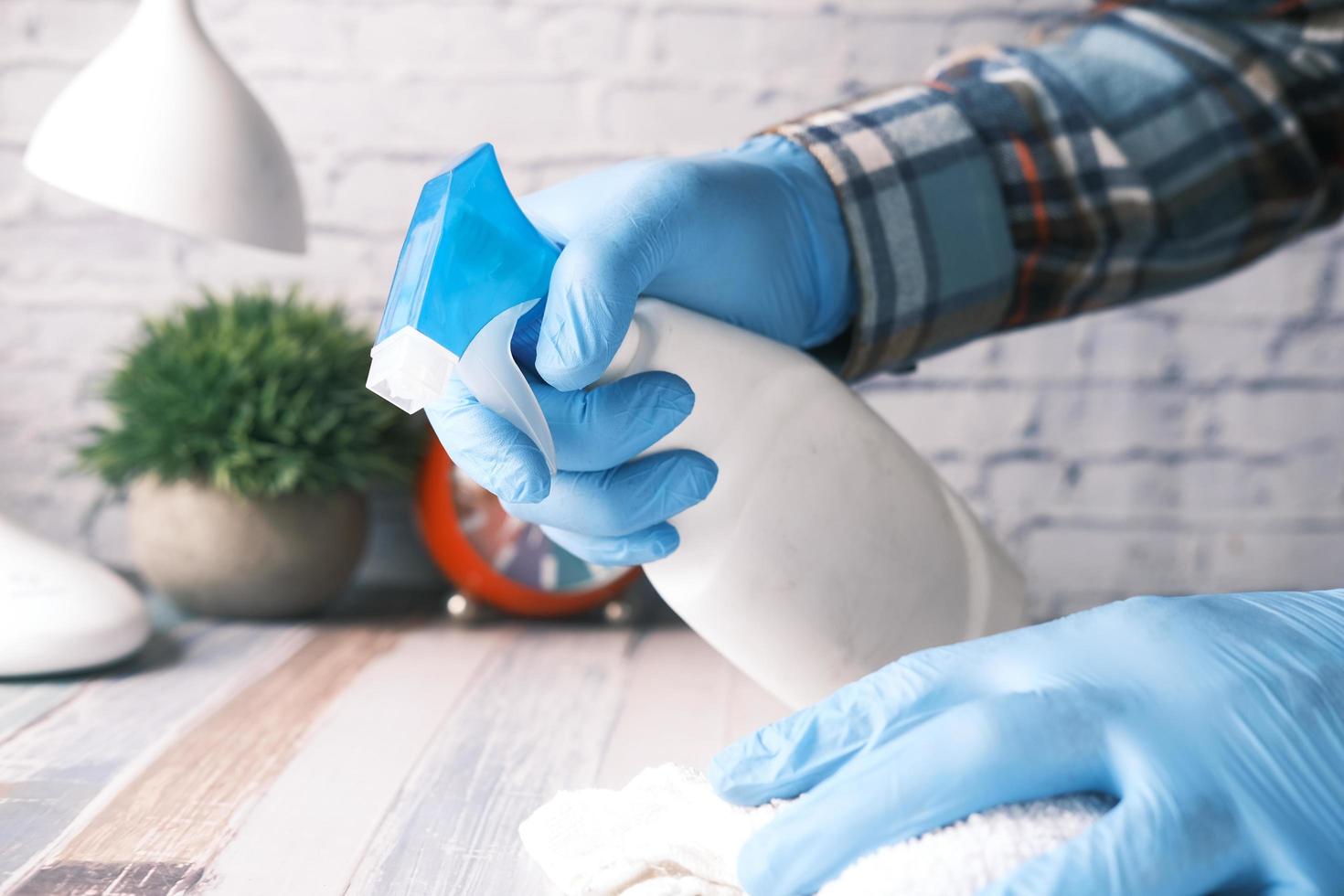 hand in blauwe rubberen handschoenen met spuitfles reinigingstafel foto
