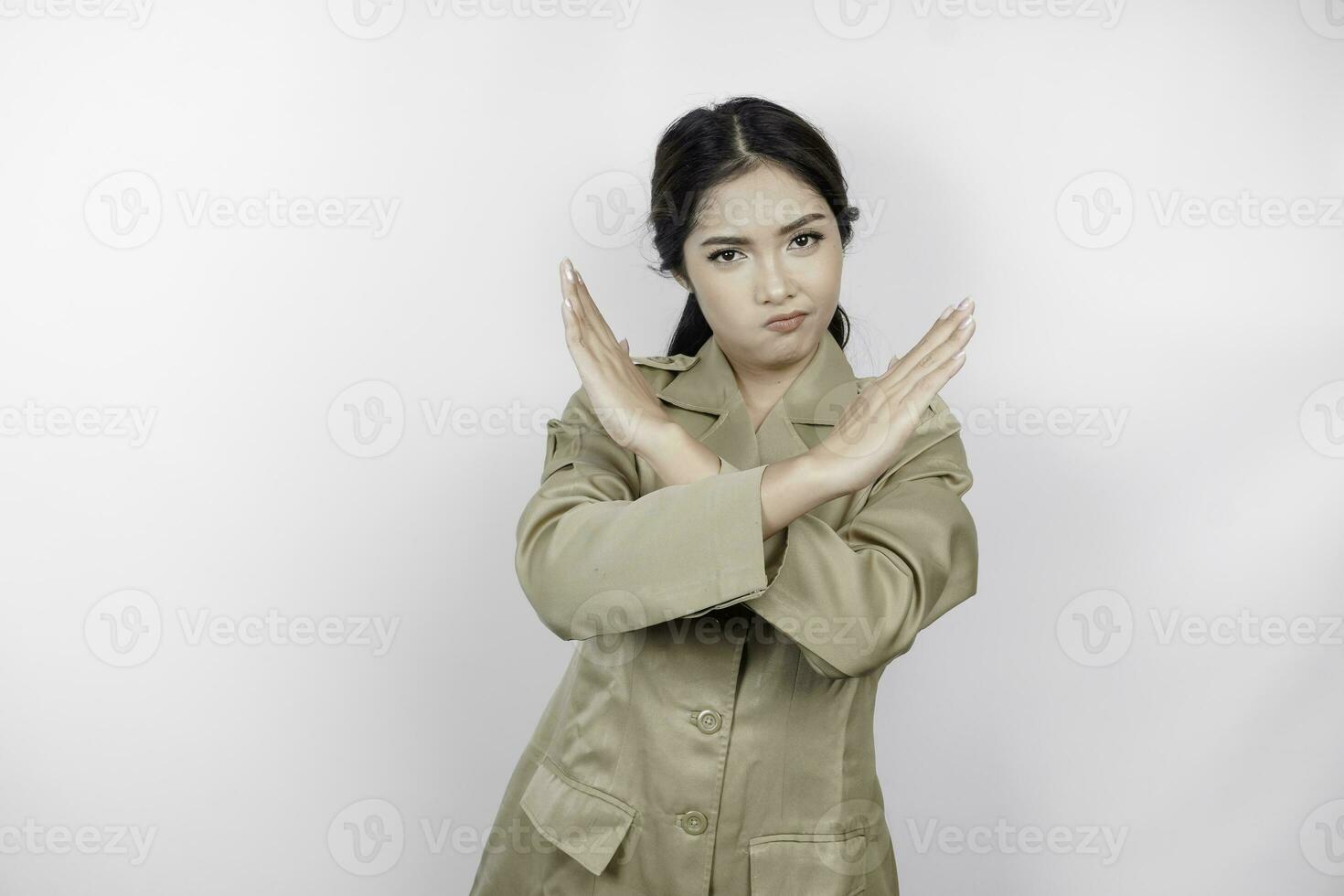 jong Aziatisch vrouw vervelend een bruin uniform shows gekruiste handen of hou op gebaar, geïsoleerd wit achtergrond foto