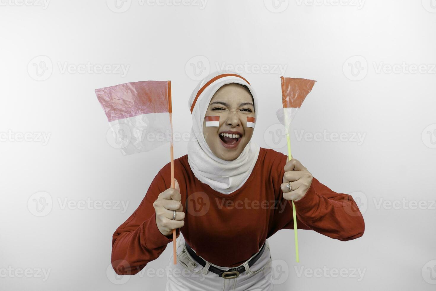 een jong Aziatisch moslim vrouw met een gelukkig geslaagd uitdrukking vervelend rood top en wit hijab terwijl Holding Indonesië's vlag, geïsoleerd door wit achtergrond. Indonesië's onafhankelijkheid dag concept. foto
