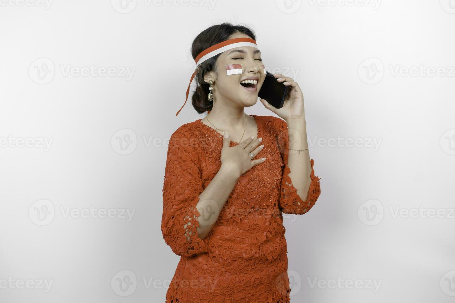 gelukkig bedachtzaam dankbaar jong Aziatisch vrouw vervelend rood kebaya en Holding telefoon en hand- Aan borst glimlachen geïsoleerd Aan wit achtergrond gevoel Nee spanning, foto