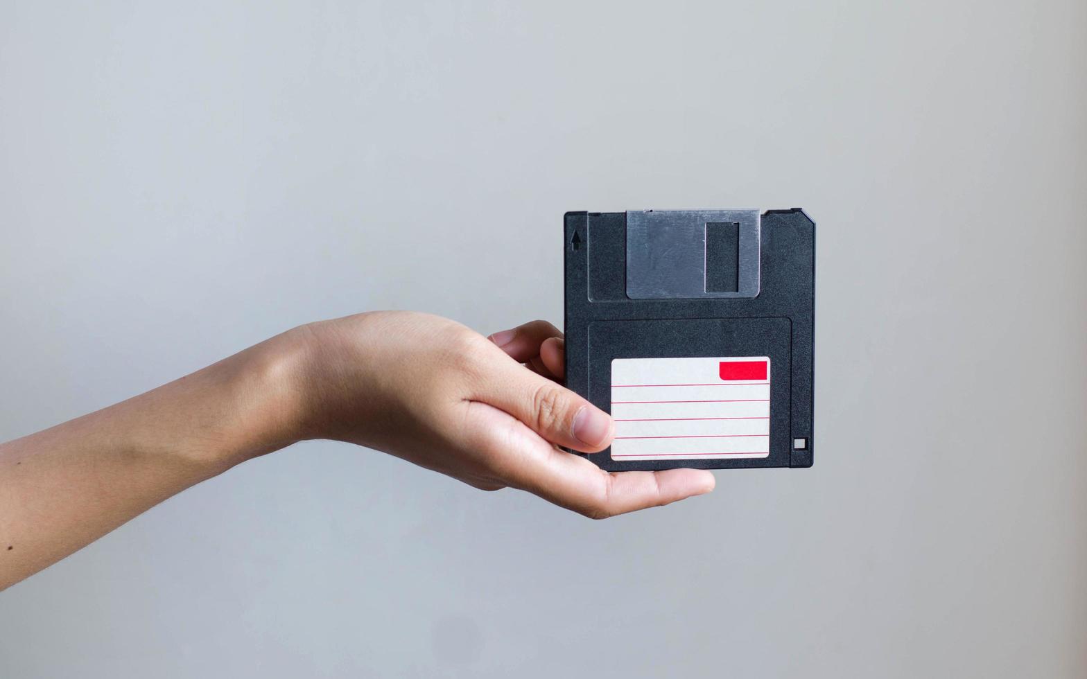 close-up afbeelding hand met zwarte floppy disk gegevensopslag foto