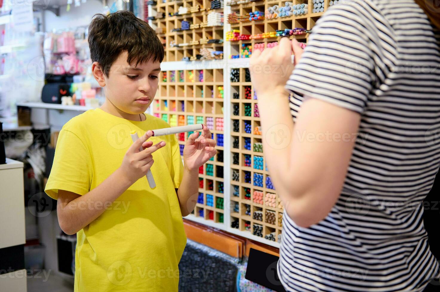 echt tiener- jongen kiest waterverf markeringen in school- schrijfbehoeften op te slaan, vraagt een verkoop manager voor helpen foto