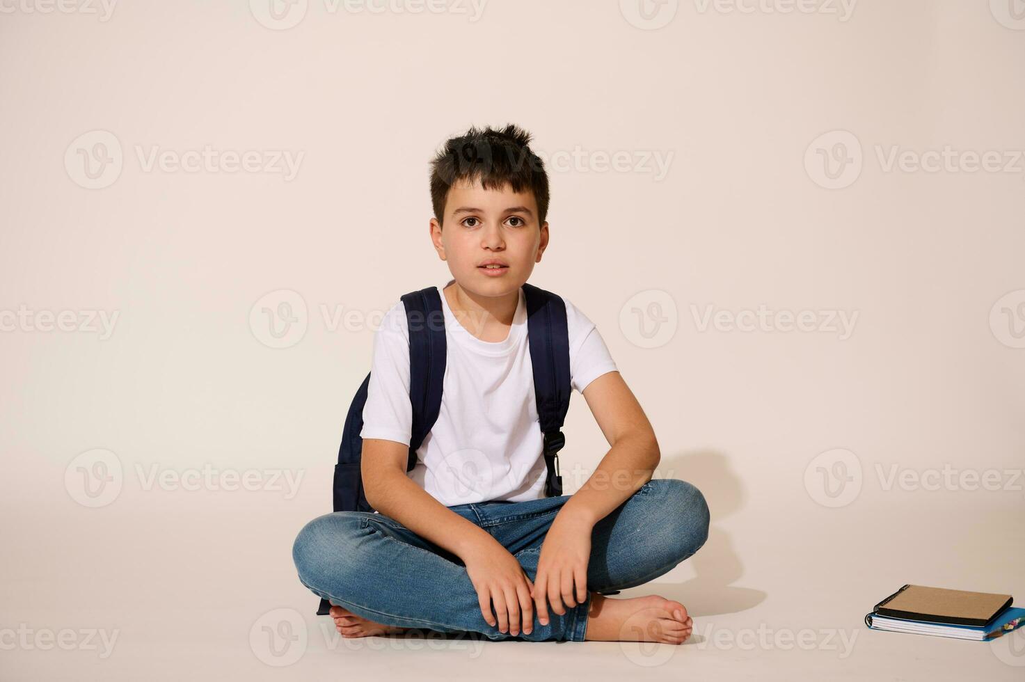 knap tiener, primair school- leerling zittend tegen een wit studio achtergrond, op zoek vol vertrouwen Bij camera. foto