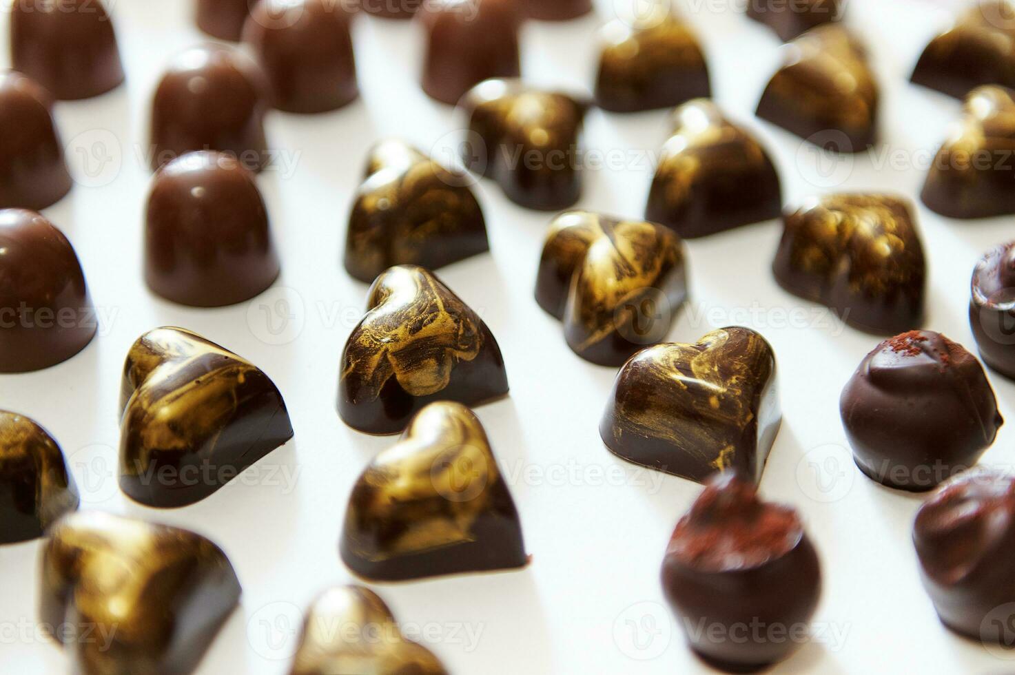 assortiment van mooi luxueus belgisch chocola snoepjes, truffels en pralines met gouden ornament in hart vorm Aan een wit achtergrond foto