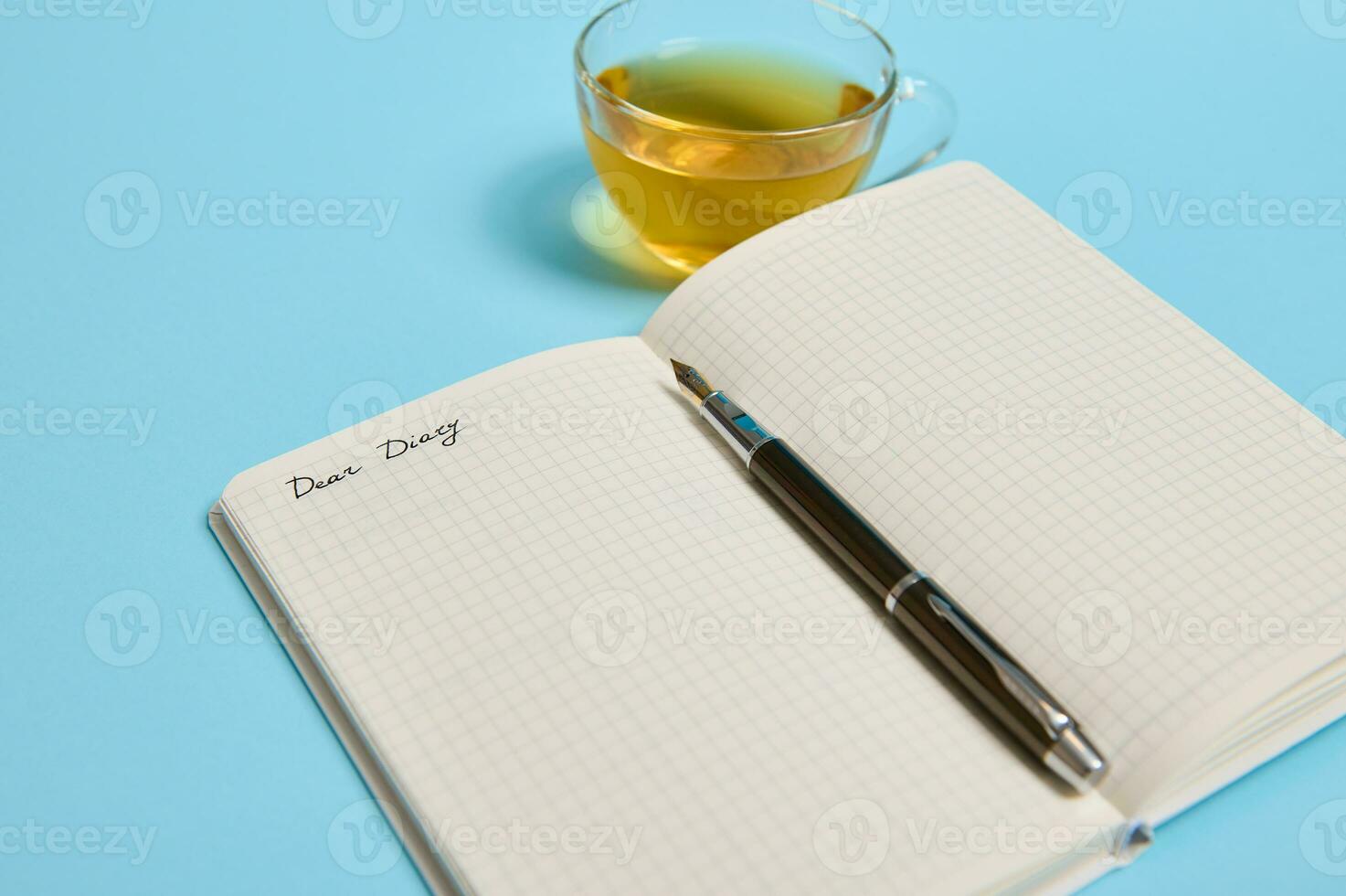 Open kladblok met woord Lieve dagboek en een inkt pen De volgende naar een thee kop Aan blauw achtergrond met kopiëren ruimte foto