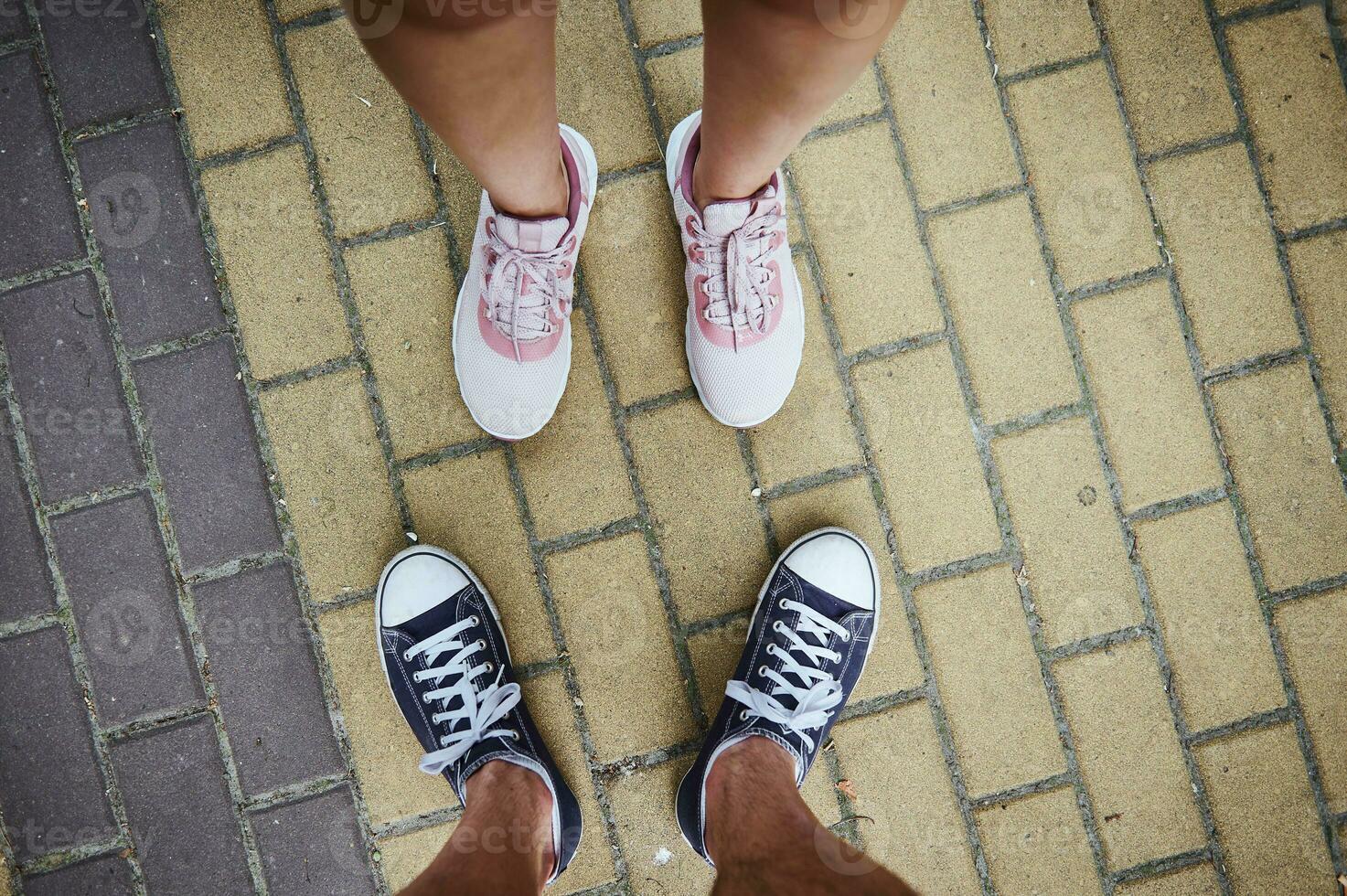 top visie van mannetje en vrouw poten in sportschoenen, staand Aan stoep. selectief focus. detailopname. kopiëren reclame ruimte foto