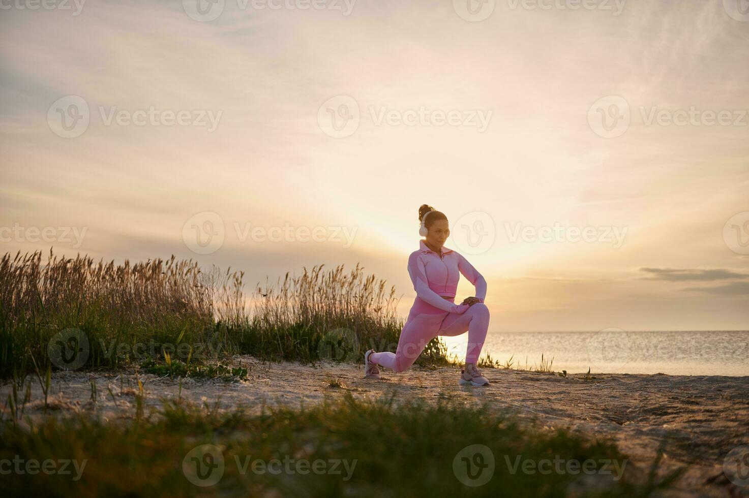 jong atleet verwarmt omhoog Bij de estuarium voordat een avond rennen Bij zonsondergang. buitenshuis training concept foto