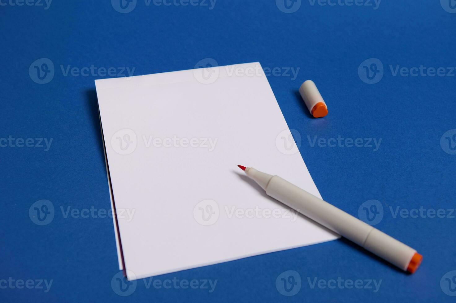 hoog hoek visie van een samenstelling met waterverf markeerstift of viltstift pennen Aan wit blanco vel van papier met kopiëren ruimte voor tekst geïsoleerd Aan blauw achtergrond. foto