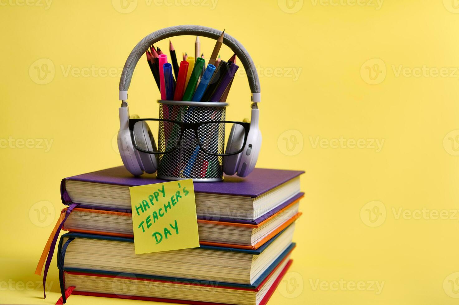 samenstelling van een stack van kleurrijk boeken potloden bril draadloze hoofdtelefoons Notitie papier met belettering leraren dag Aan een geel achtergrond met kopiëren ruimte. terug naar school- concepten. foto