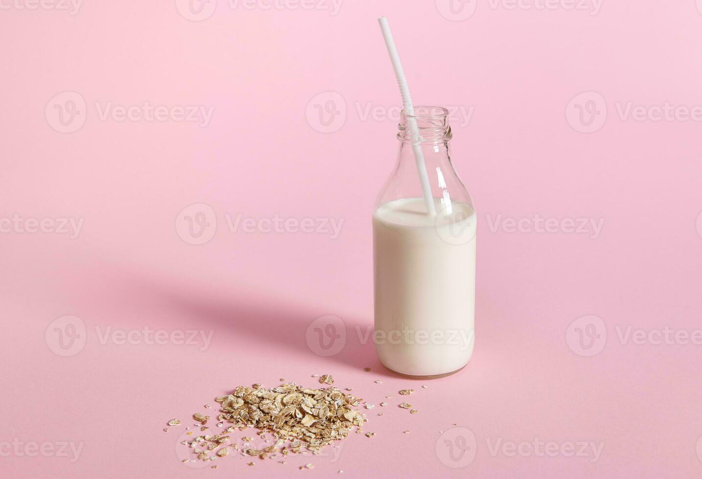 detailopname visie van glas fles met melk en haver vlokken Aan roze achtergrond met ruimte voor tekst foto