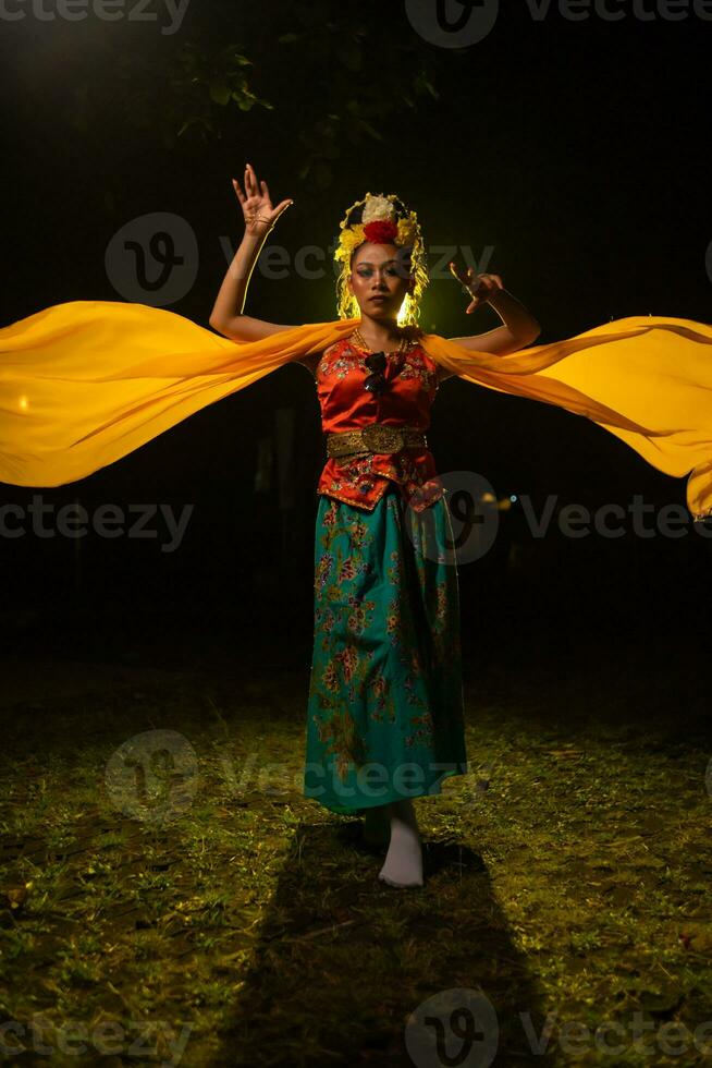 een traditioneel Indonesisch danser dansen met een geel sjaal dat drijft in de lucht foto