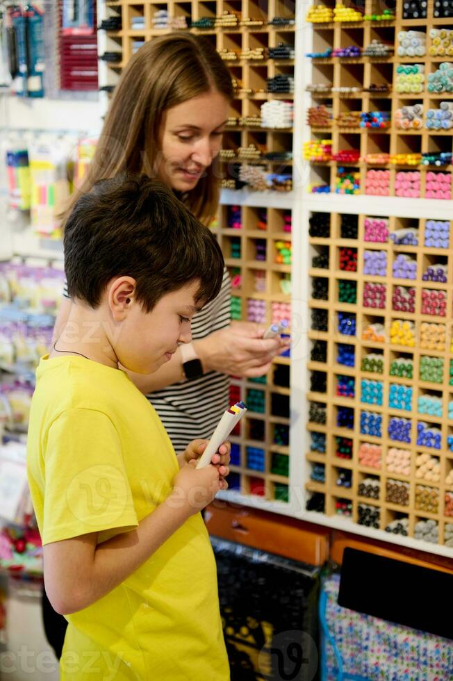 glimlachen vrouw verkoper tonen kleurrijk levendig waterverf viltstiften naar een tiener schooljongen wie is boodschappen doen in kunst op te slaan foto