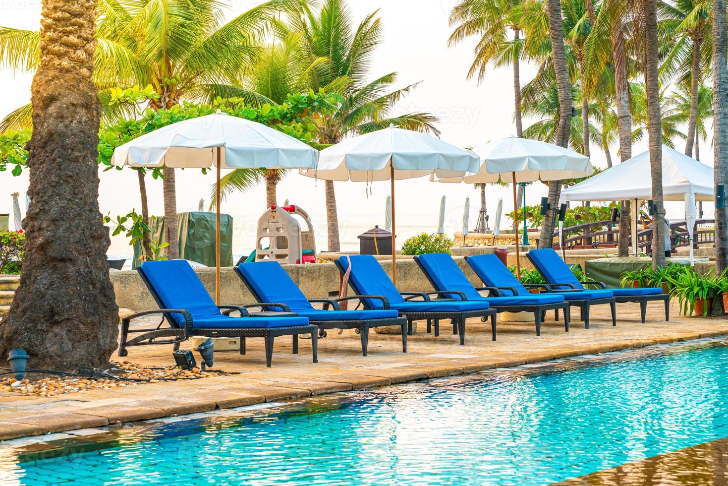mooie parasol en stoel rond zwembad in hotel en resort foto