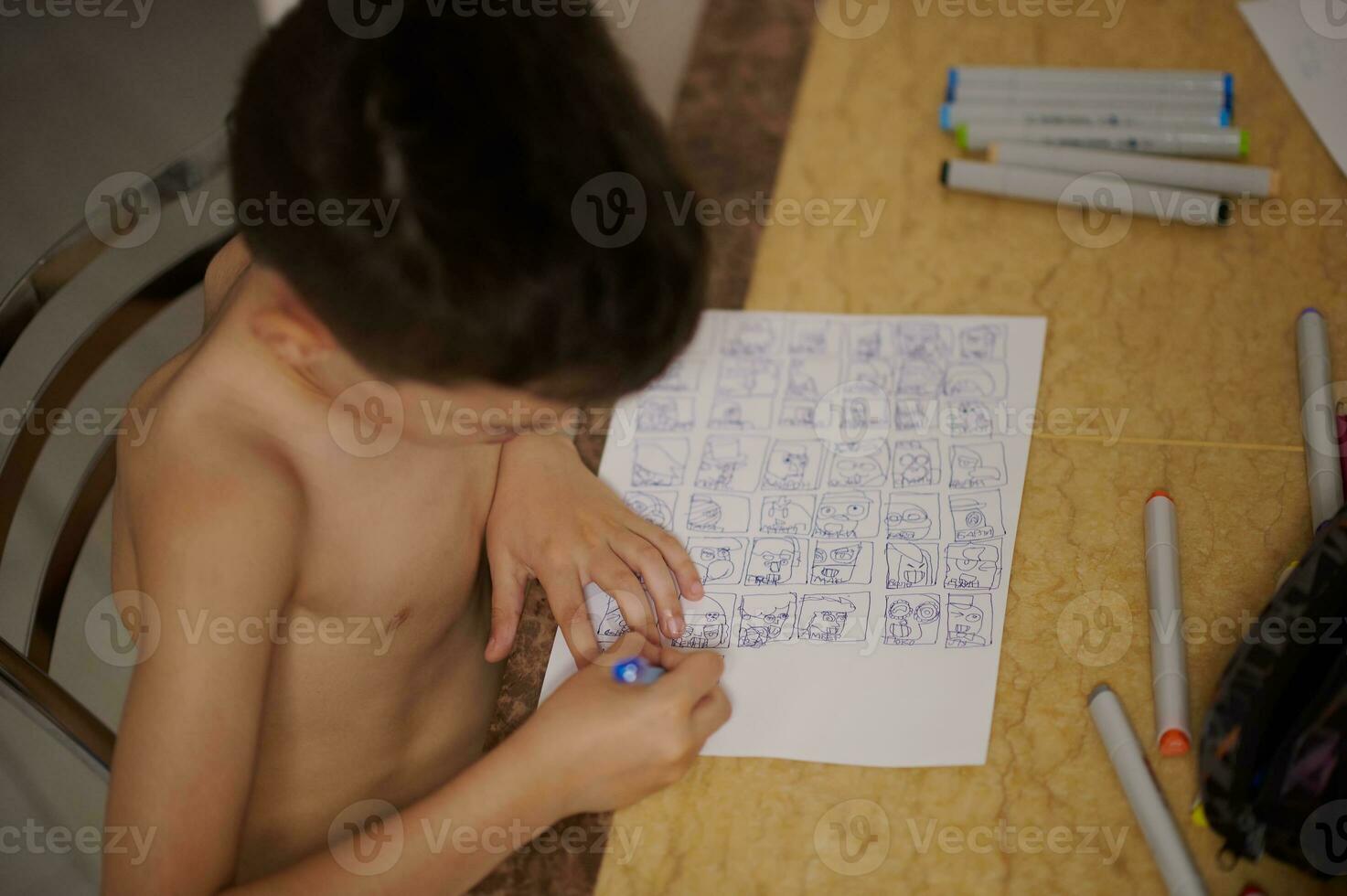 top visie van jongen Bij tafel tekening comics en tekenfilms Aan wit vel van papier foto