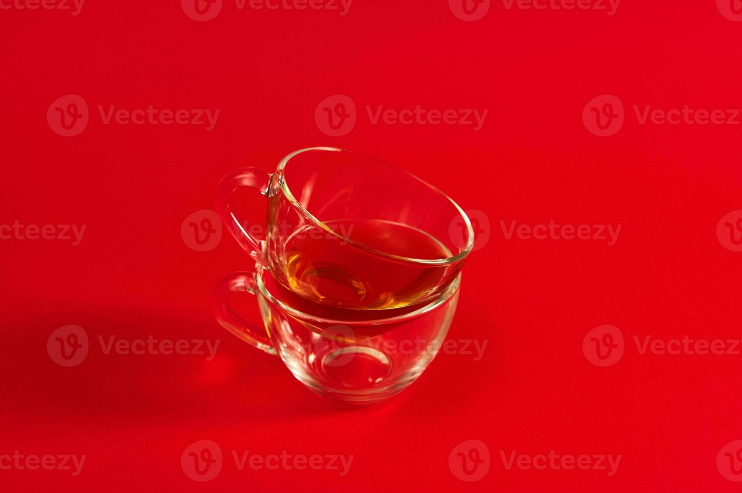 twee transparant glas cups Aan een rood oppervlak. schot met zacht schaduw Aan rood achtergrond met kopiëren ruimte foto