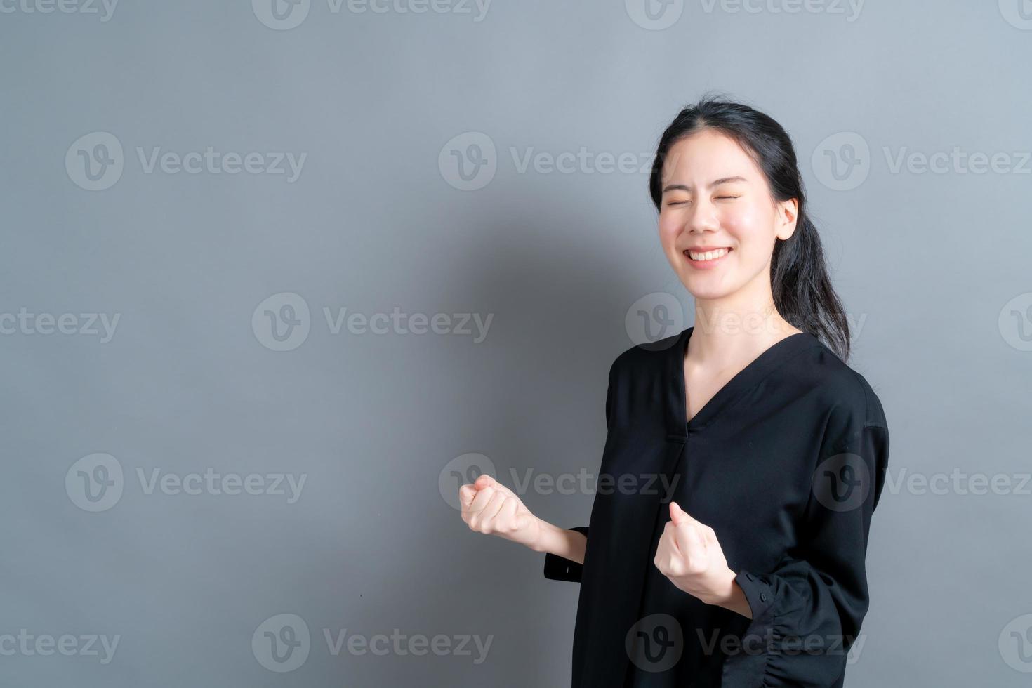 aziatische vrouw die zich verheugt over haar succes en overwinning balde haar vuisten van vreugde. gelukkige vrouw die blij is om haar doel en doelen te bereiken. positieve emoties, gevoelens. foto