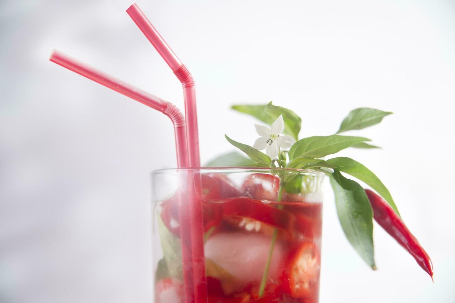 een glas gevulde met rood paprika's en een rietje foto