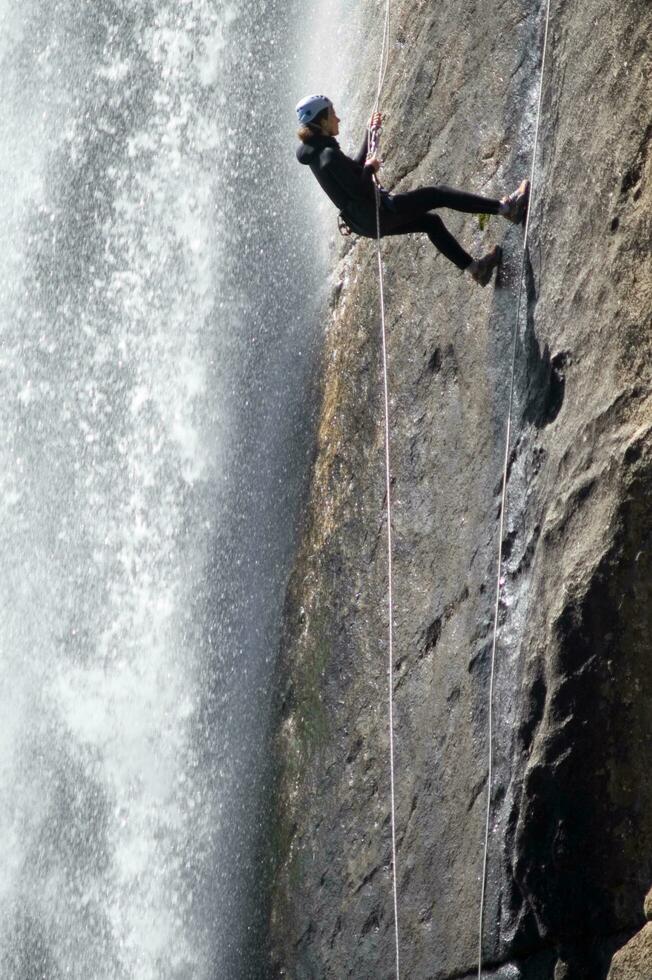 een persoon Aan een touw beklimming omhoog een waterval foto