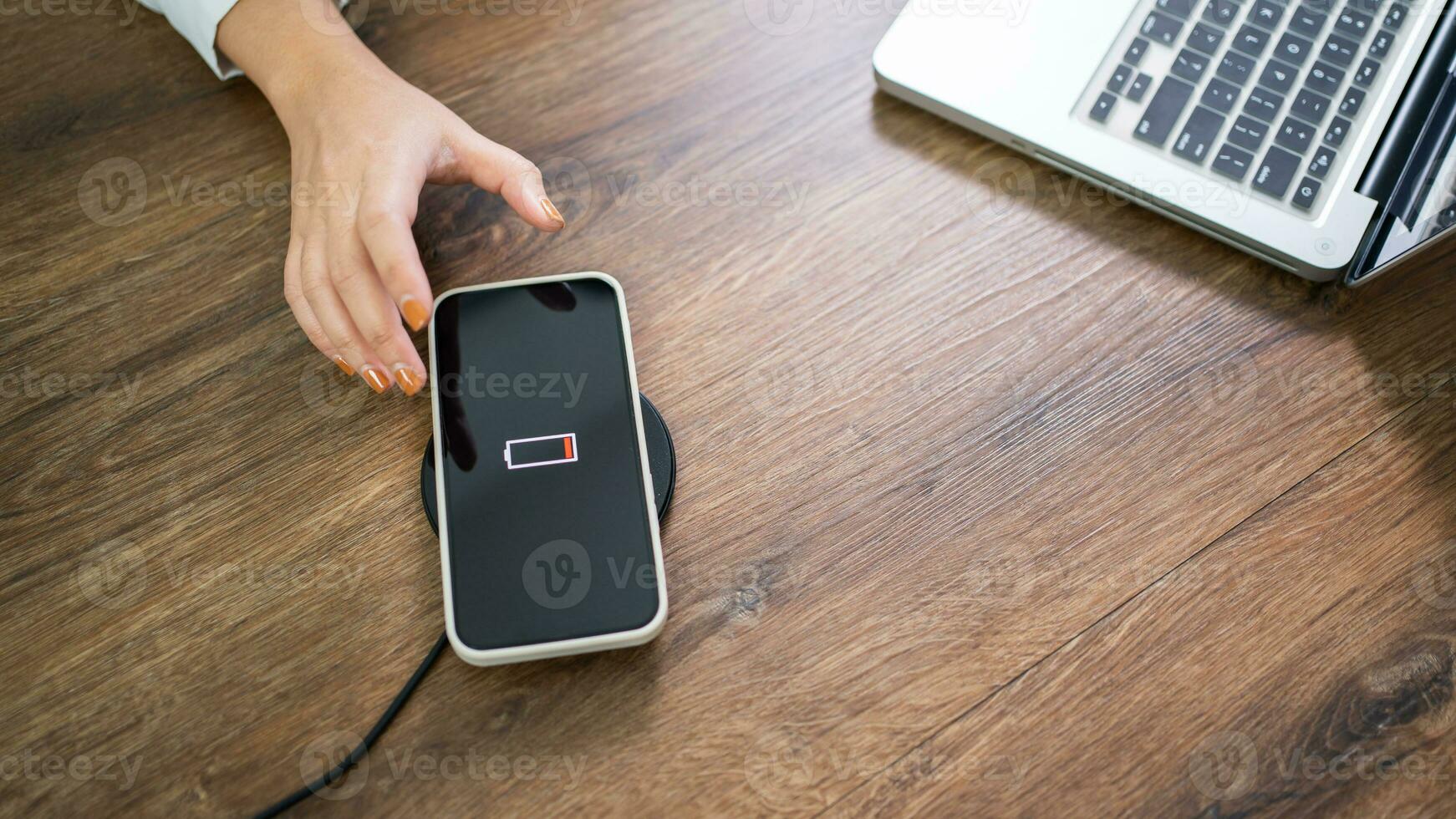 opladen mobiel telefoon accu met draadloze opladen apparaat in de tafel. smartphone opladen Aan een opladen kussen. mobiel telefoon in de buurt draadloze oplader modern levensstijl technologie concept. foto