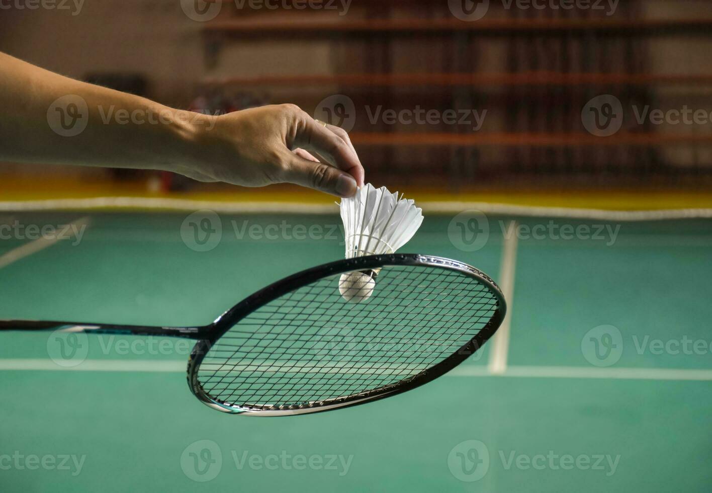 badminton speler houdt racket en wit room shuttle in voorkant van de netto voordat portie het naar een ander kant van de rechtbank foto