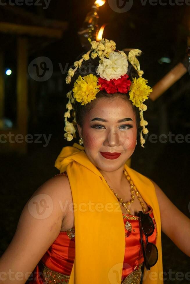 een traditioneel Javaans danser dansen met kleurrijk bloemen Aan haar vuist terwijl Aan stadium foto