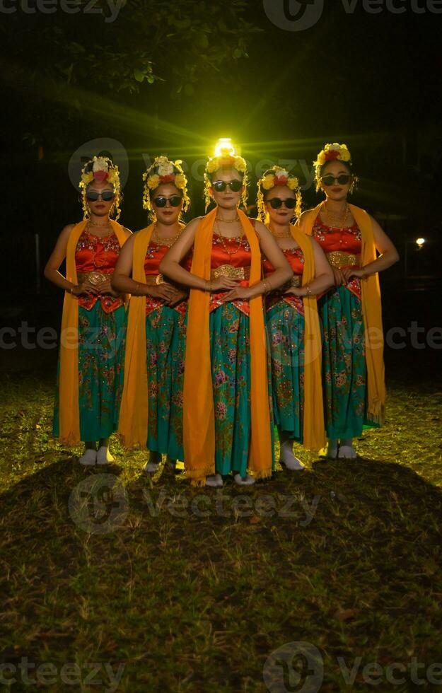 een groep van Indonesisch traditioneel dansers dans met hun vrienden in voorkant van de stadium lichten foto