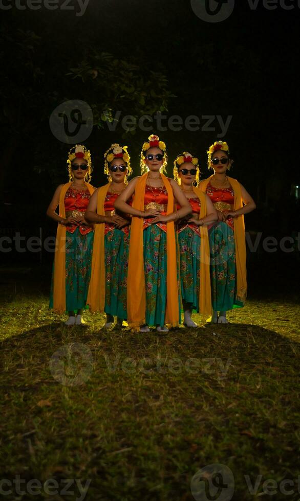 een groep van Indonesisch traditioneel dansers dans met hun vrienden in voorkant van de stadium lichten foto