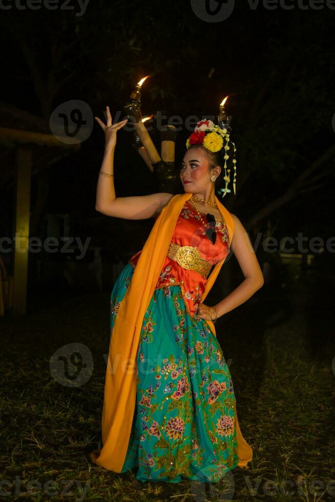 een traditioneel Aziatisch danser poses in voorkant van een brandend fakkel in een oranje kostuum welke is heel mooi foto