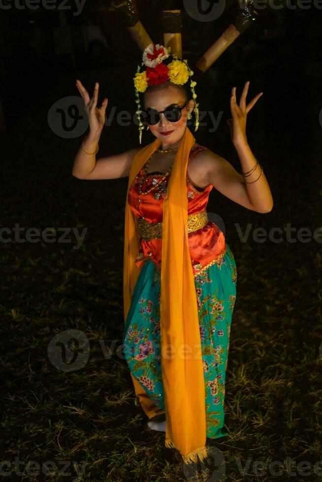 een Indonesisch traditioneel danser dansen in zonnebril en een oranje kostuum met een mooi sjaal foto