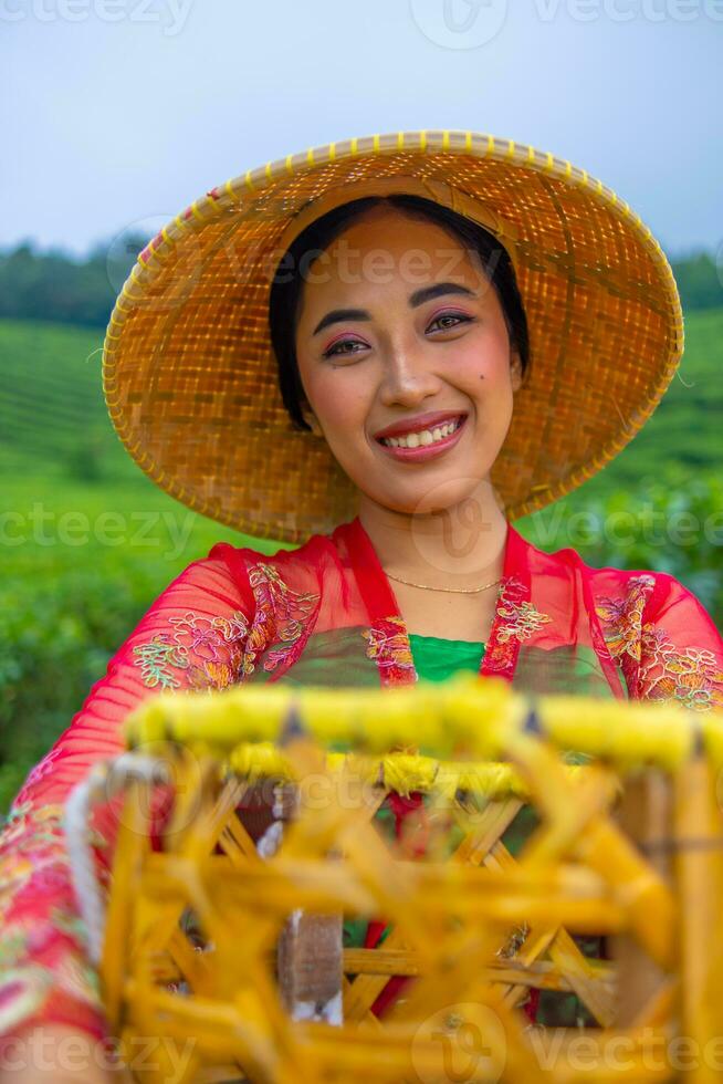 een thee blad boer is genieten van de visie van de thee tuin terwijl Holding een mand foto