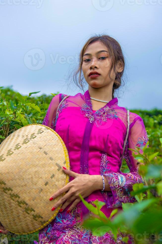 een Indonesisch vrouw in een roze jurk Holding een bamboe hoed in haar handen foto