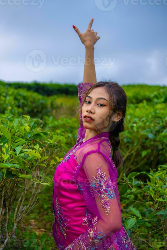 een Aziatisch vrouw poseren heel sexy tussen de thee plantages terwijl vervelend een roze jurk foto