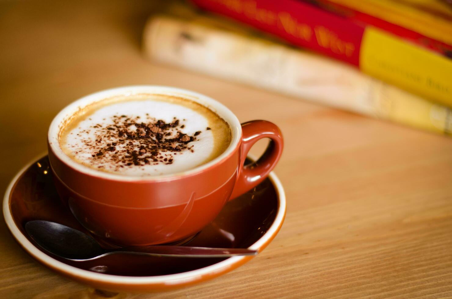 kop van cappuccino koffie en boeken in knus cafe foto