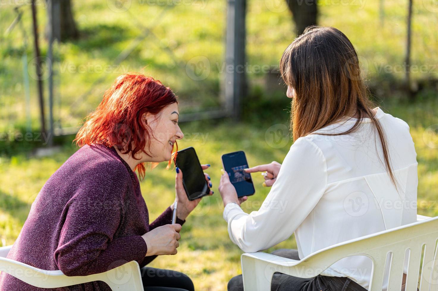 vriendinnen die smartphone gebruiken en sigaretten roken foto