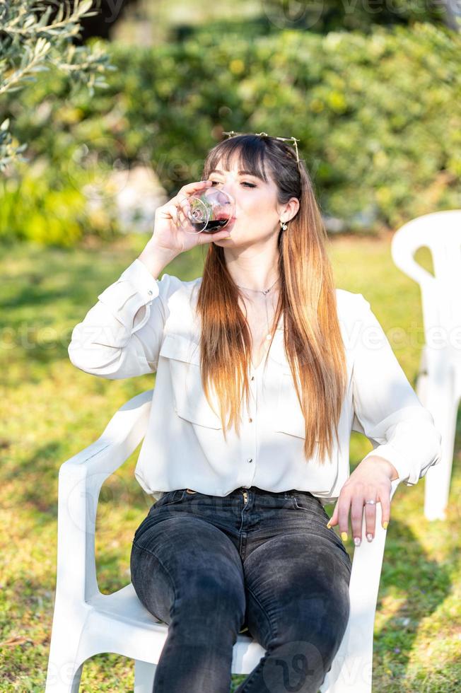 meisje drinkt beker rode wijn in de tuin foto