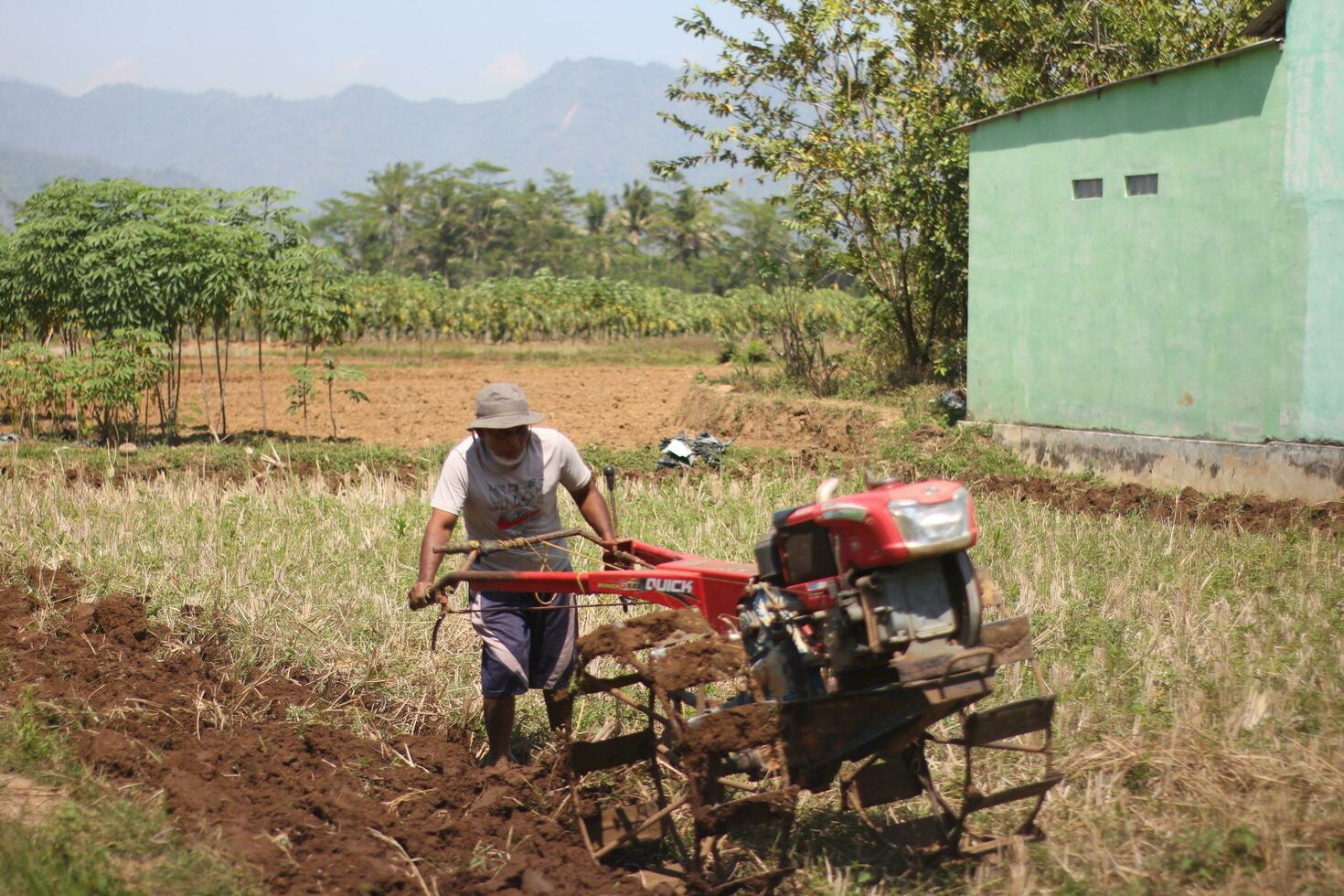 magelang indonesië.07302023-a boer is ploegen een veld- met een modern gereedschap in de het formulier van een tractor. foto