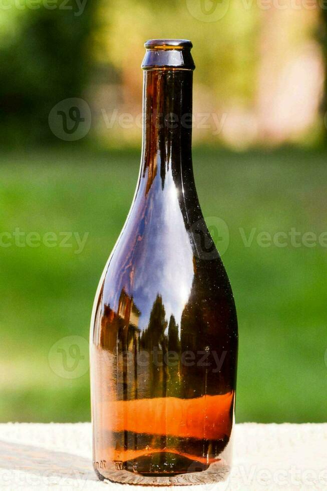 een bruin glas fles zittend Aan een houten tafel foto