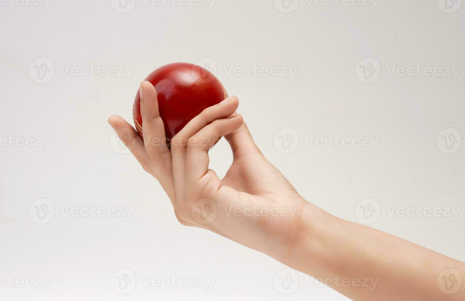 een vrouw hand- Holding een rood test bij elkaar passen leer steek krekel bal detailopname afbeelding wit achtergrond foto