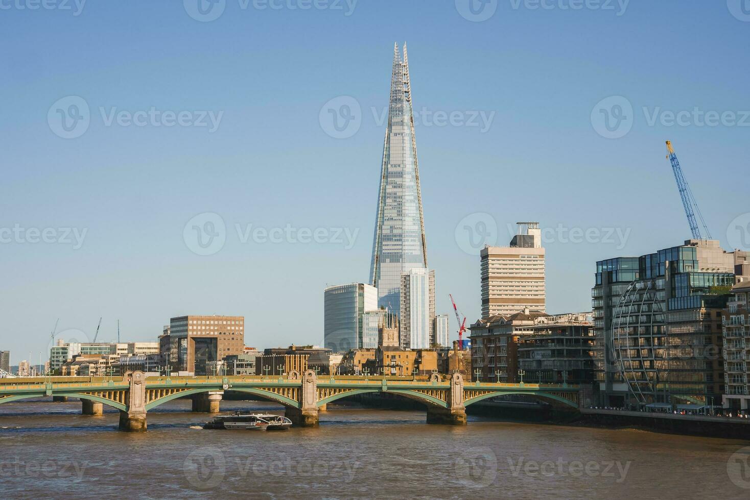 scherf toren temidden van gebouwen door rivier- Theems in stad Aan zonnig dag foto