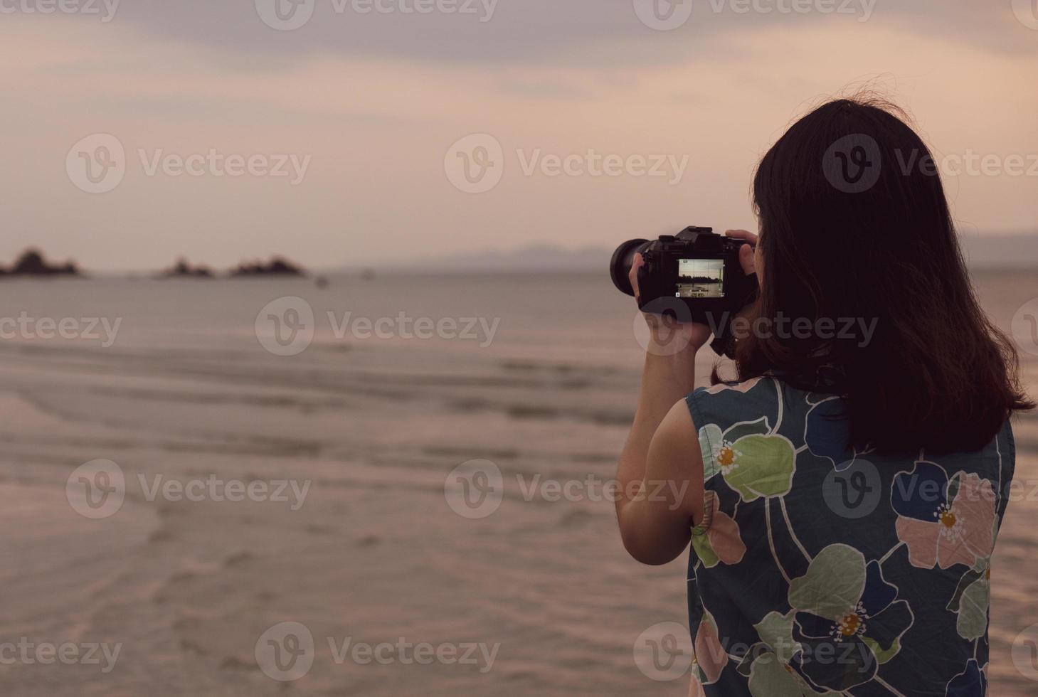 portret van een jonge vrouw die camera gebruikt om foto's te maken van het strand tijdens de zomervakantie foto