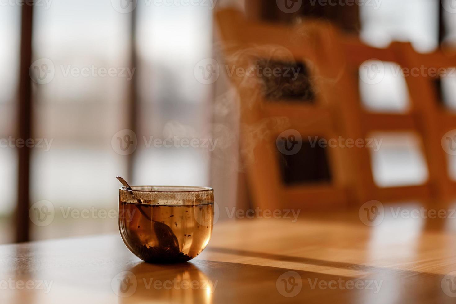 kopje thee met stoom op houten tafel in de woonkamer. selectieve focus foto