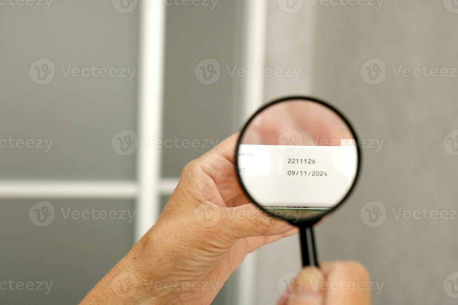 handen van een ouderen Mens onderzoeken de vervaldatum datum van geneesmiddelen met een vergroten glas foto
