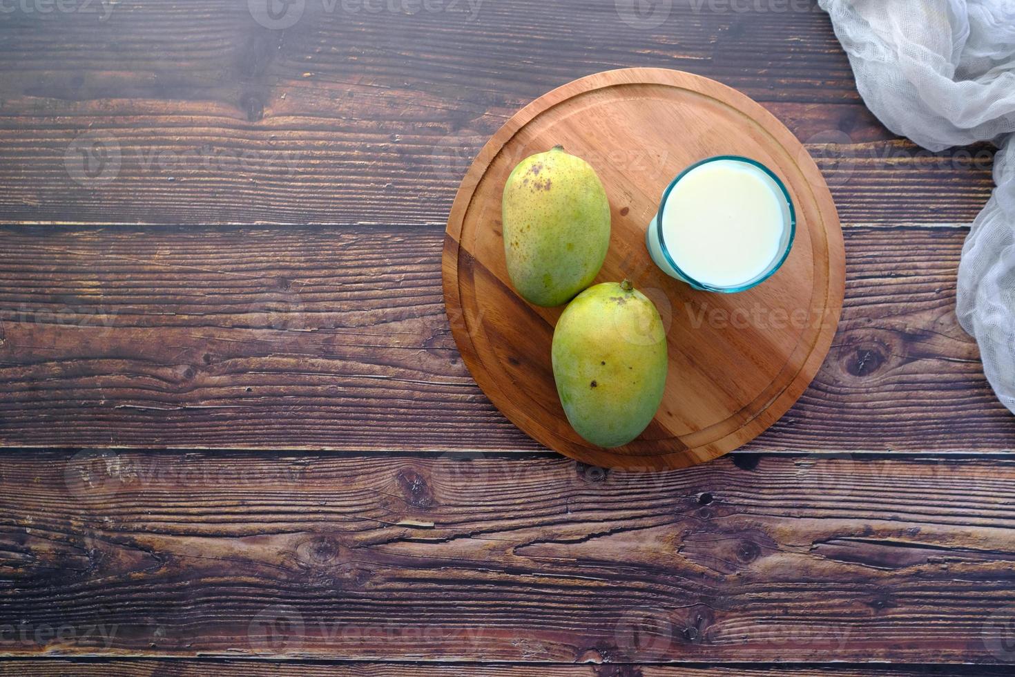 verse rijpe mango en glas melk op tafel foto